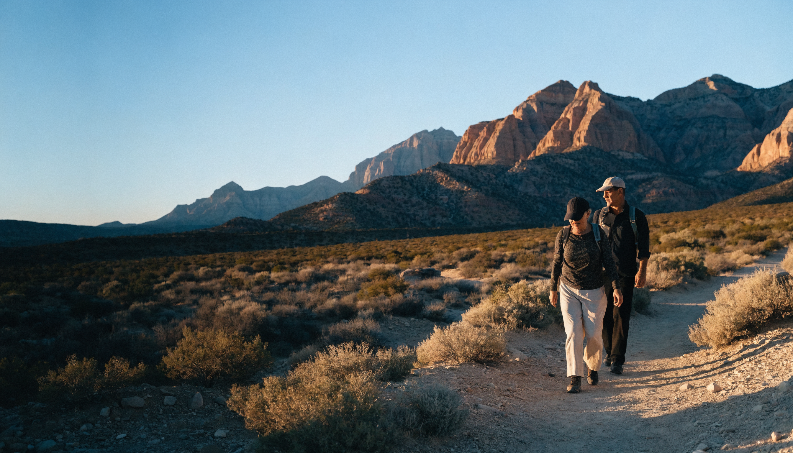 Two people walking a desert trail at sunrise outside Las Vegas