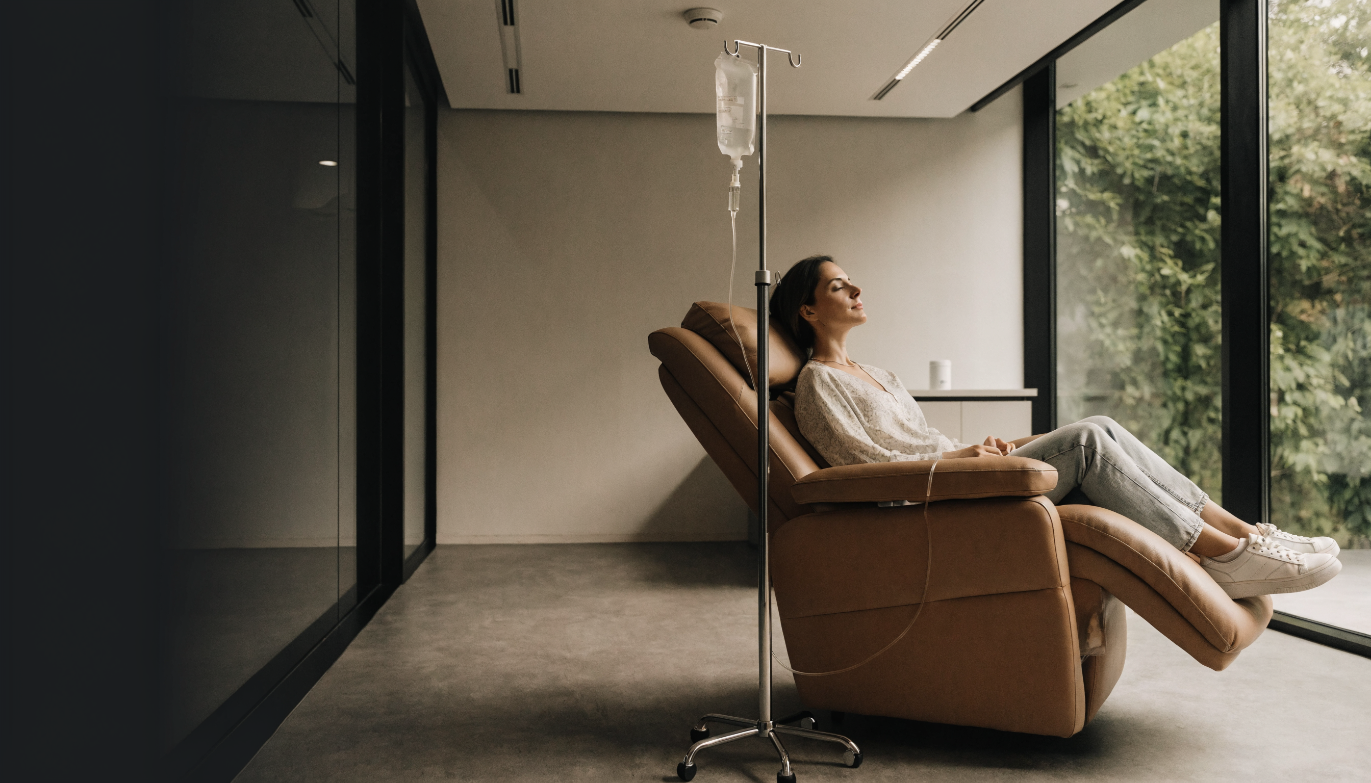 A patient seated comfortably in a treatment chair receiving an IV drip in a bright clinic